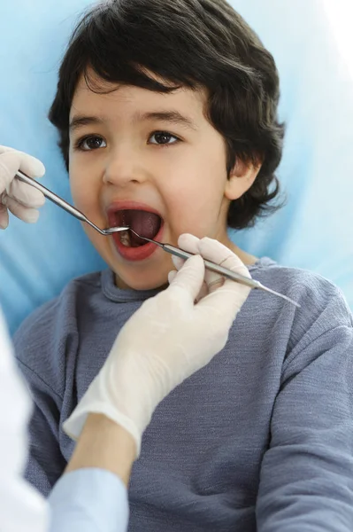 Pequeño chico árabe sentado en la silla dental con la boca abierta durante la revisión oral con el médico dentista. Concepto de estomatología — Foto de Stock