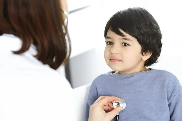 Doctor-woman examining a child patient by stethoscope. Cute arab boy at physician appointment. Medicine concept — Stock Photo, Image