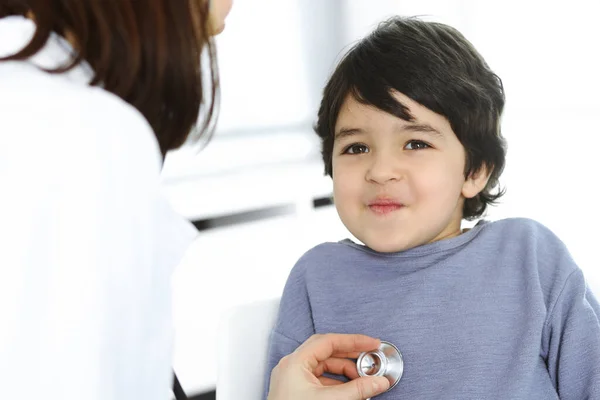 Médico-mujer examinando a un niño paciente por estetoscopio. Lindo chico árabe en la cita con el médico. Concepto de medicina — Foto de Stock