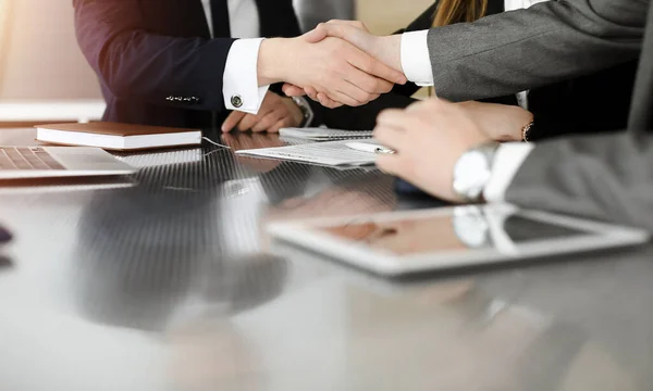 Hombre de negocios desconocido estrechando la mano con su colega o compañero por encima del escritorio en la oficina soleada, primer plano — Foto de Stock
