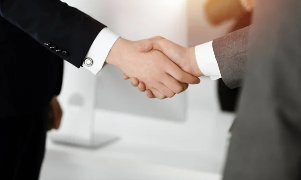 Hombre de negocios desconocido estrechando la mano con su colega o pareja mientras está de pie en la oficina soleada, primer plano — Foto de Stock