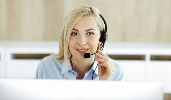 Mujer rubia de negocios sentada y comunicada por auriculares en la oficina del centro de llamadas. Concepto de negocio de telesales u ocupación de oficina en el hogar — Foto de Stock
