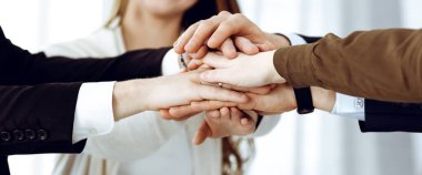 Takım çalışması yapan ve el ele tutuşan iş adamları grubu ya da modern ofiste beş kişi. Bilinmeyen işadamı ve kadınlar elleriyle daire çiziyorlar.