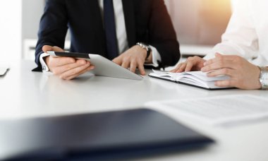 Bilinmeyen iş adamları güneşli ofiste tablet bilgisayar kullanıyorlar. İş adamı, meslektaşı ile birlikte çalışıyor, yakın plan.