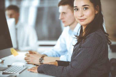İş kadını ve erkek, modern ofiste bilgisayar kullanırken soruları tartışıyorlar. Takım çalışması, toplantı ve beyin fırtınası konsepti