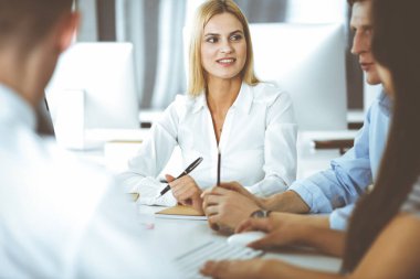 Bir grup iş adamı toplantıda soruları tartışıyor. Ofis görüşmelerinde iş arkadaşına gülümseyen sarışın iş kadınının vesikalığı. Şirket işgalinde takım çalışması ve işbirliği