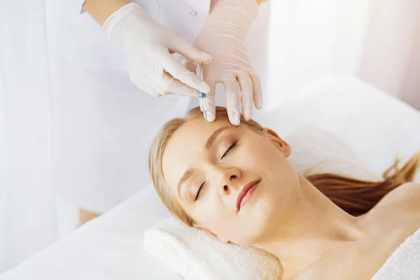 Beautician arts doet schoonheidsbehandeling met spuit naar blanke vrouwelijke gezicht in synny kamer. Cosmetische geneeskunde en chirurgie, schoonheidsinjecties concept — Stockfoto