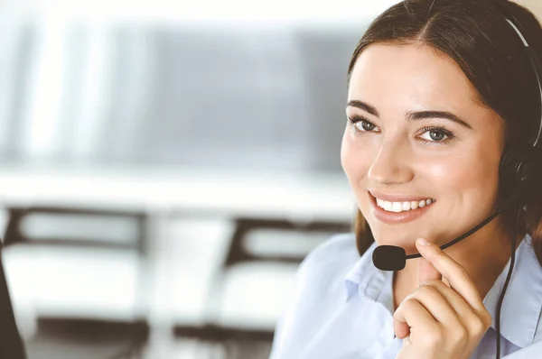 Brunett kvinnlig kundservice representant i ett headset konsulterar kunder på nätet. Begreppet callcenter och affärsmän — Stockfoto