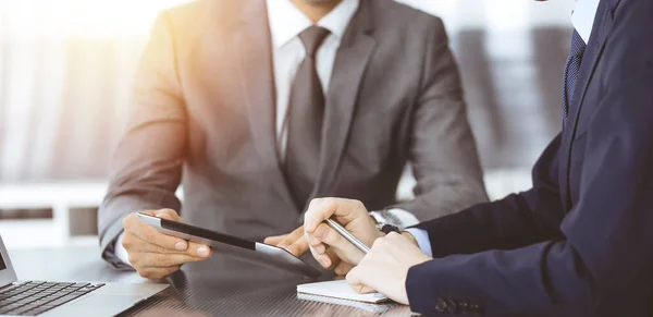 Hombre de negocios desconocido que utiliza la computadora de la tableta y el trabajo junto con su colega mientras se sienta en el escritorio de cristal en la oficina moderna. Trabajo en equipo y concepto de asociación — Foto de Stock