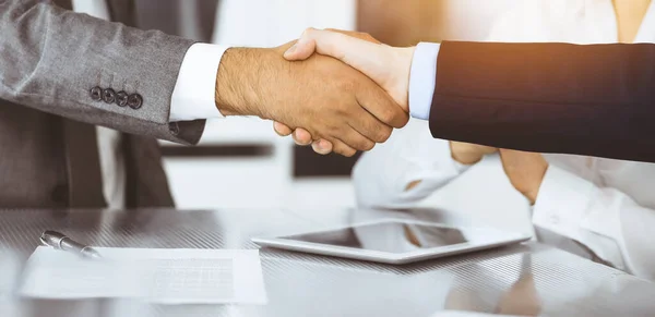 Handshake as successful negotiation ending, close-up. Unknown business people shaking hands after contract signing in modern office