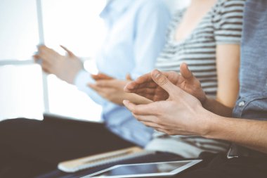 İş adamları toplantı ya da konferansta el çırpıyor. Modern beyaz ofisteki bir grup tanınmayan iş adamı ve kadın. Başarı takım çalışması, kurumsal koçluk ve alkış konsepti