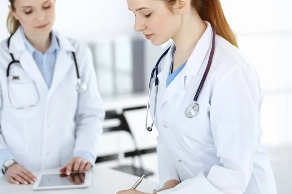 Doctora en el trabajo. Médico o estudiante interna llenando documentos médicos o prescripción mientras está de pie en la recepción de la clínica. Datos en medicina — Foto de Stock