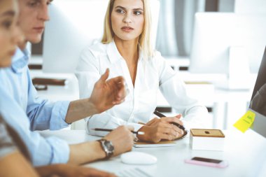 Bir grup iş adamı toplantıda soruları tartışıyor. Ofis görüşmelerinde iş arkadaşına gülümseyen sarışın iş kadınının vesikalığı. Şirket işgalinde takım çalışması ve işbirliği