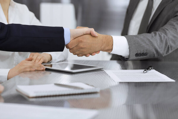 Handshake as successful negotiation ending, close-up. Unknown business people shaking hands after contract signing in modern office