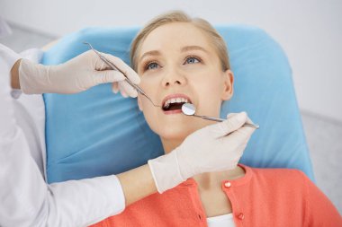 Gülümseyen beyaz kadın dişçi kliniğinde dişçi tarafından muayene ediliyor. Sağlıklı dişler ve ilaçlar, stomatoloji konsepti