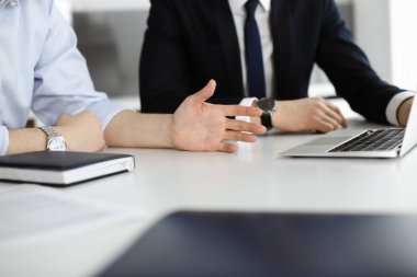 Bilinmeyen iş adamları modern ofisteki masada dizüstü bilgisayar kullanıyorlar. İş adamı ya da erkek girişimci meslektaşı ile birlikte çalışıyor. Takım çalışması ve ortaklık kavramı