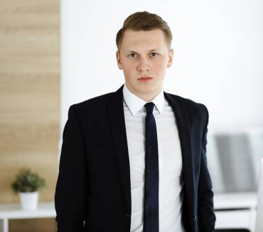 Ofisteki kameraya bakıp duran neşeli iş adamı. Genç ve başarılı girişimcinin vesikalığı