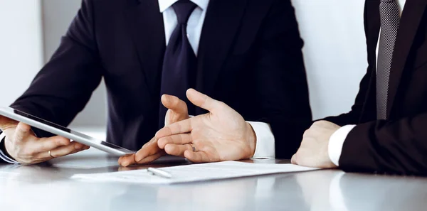 Gente de negocios que usa tableta mientras trabajan juntos en la oficina moderna. Hombre de negocios desconocido con colega en el lugar de trabajo. Trabajo en equipo y concepto de asociación — Foto de Stock