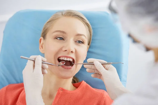 Mujer caucásica sonriente está siendo examinado por el dentista en la clínica dental. Dientes sanos y medicina, concepto de estomatología — Foto de Stock