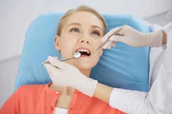 Smiling caucasian woman is being examined by dentist at dental clinic. Healthy teeth and medicine, stomatology concept — Stock Photo, Image