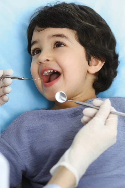 Petit garçon arabe assis à la chaise dentaire avec la bouche ouverte pendant le contrôle oral avec le médecin dentiste. Concept de stomatologie — Photo