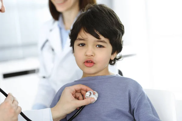 Médico-mujer examinando a un niño paciente por estetoscopio. Lindo chico árabe en la cita con el médico. Concepto de medicina —  Fotos de Stock