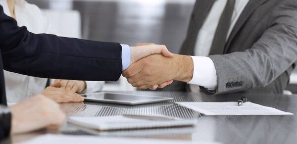 Handshake as successful negotiation ending, close-up. Unknown business people shaking hands after contract signing in modern office
