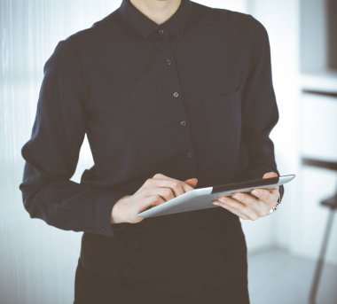 Bilinmeyen iş kadını ofiste dikilirken tablet bilgisayar kullanıyor, yakın plan. Ticarette veri