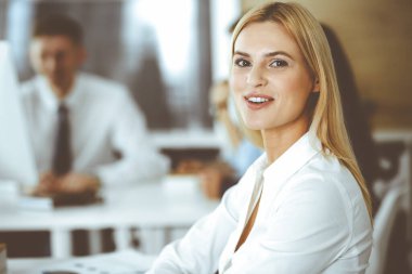 Modern ofisteki işyerinde bilgisayar kullanan bir iş kadını. Sekreter ya da kadın avukat gülümsüyor ve mutlu görünüyor. Zevk ve başarı için çalışmak