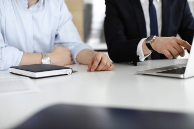 Bilinmeyen iş adamları modern ofisteki masada dizüstü bilgisayar kullanıyorlar. İş adamı ya da erkek girişimci meslektaşı ile birlikte çalışıyor. Takım çalışması ve ortaklık kavramı