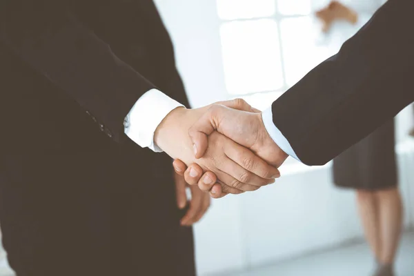 Zakenman en vrouw schudden handen met collega 's op de achtergrond. Handdruk bij de vergadering. Begrip succes in het bedrijfsleven — Stockfoto