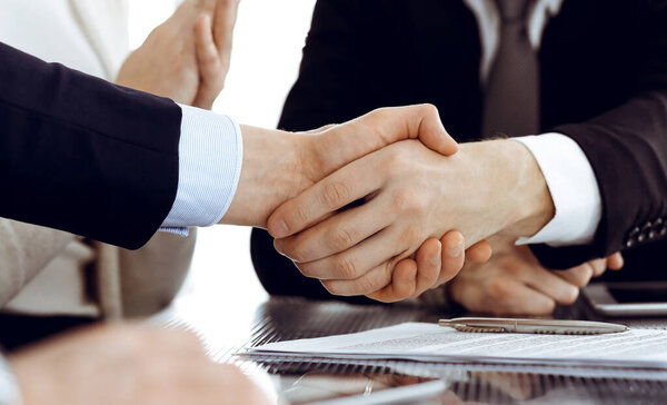 Business people shaking hands after contract signing in modern office. Teamwork, partnership and handshake concept