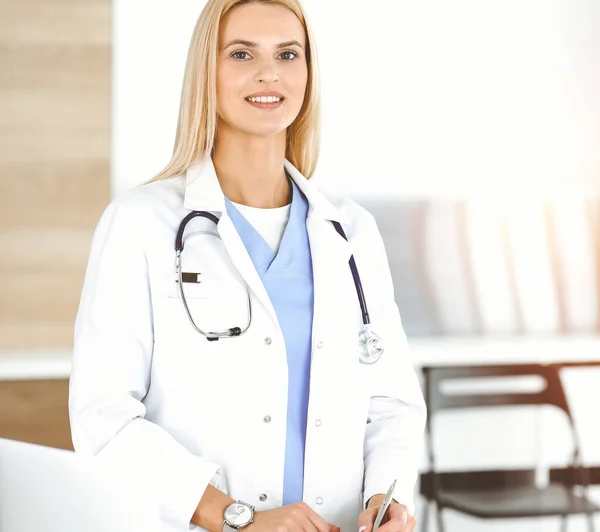 Doctor woman controls medication history records and exam results while using clipboard in sunny hospital . Medicine and healthcare concept — Stock Photo, Image