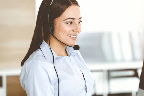 Brunette representante do serviço ao cliente feminino usando headset e clientes de consultoria on-line. Centro de atendimento — Fotografia de Stock