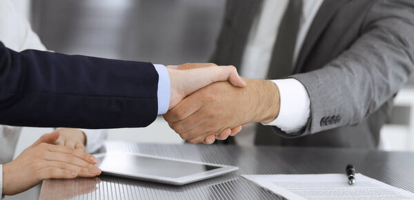 Handshake as successful negotiation ending, close-up. Unknown business people shaking hands after contract signing in modern office