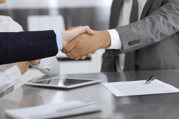 Handshake as successful negotiation ending, close-up. Unknown business people shaking hands after contract signing in modern office