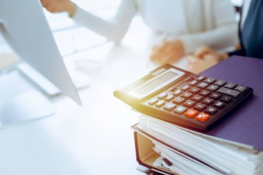 Hesap makinesi ve kağıtlar iş kadını ya da ofisteki büroda çalışan muhasebeci tarafından incelenmeyi bekliyor. İç Denetim ve vergi kavramı