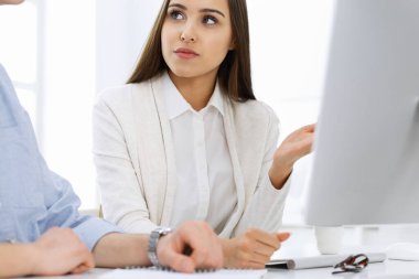 Masasında oturan genç bir kadın, beyaz renkli bir ofiste bilgisayarla. Görünüşe göre öğrenci kız ya da iş kadını sıradan giyinmiş bir adamla iletişim kuruyor.