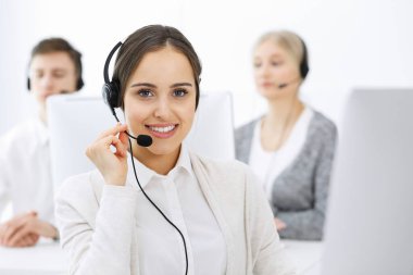 Merkezi ara. Çeşitli operatörler iş başında. Telepazarlama servisinin müşterileriyle iletişim kuran kulaklıklı güzel bir kadın. İş konsepti