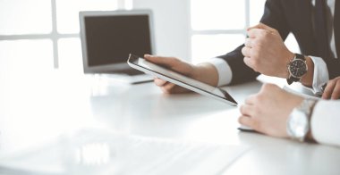Bilinmeyen iş adamları modern ofiste tablet bilgisayar kullanıyorlar. İş adamı ya da erkek girişimci, çalışma masasında meslektaşıyla birlikte çalışıyor.