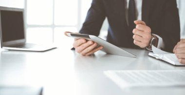 Bilinmeyen iş adamları modern ofiste tablet bilgisayar kullanıyorlar. İş adamı ya da erkek girişimci, çalışma masasında meslektaşıyla birlikte çalışıyor.