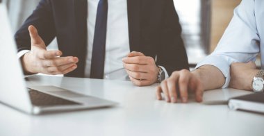 Bilinmeyen iş adamları modern ofisteki masada dizüstü bilgisayar kullanıyorlar. İş adamı ya da erkek girişimci meslektaşı ile birlikte çalışıyor. Takım çalışması ve ortaklık kavramı