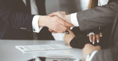 Bilinmeyen işadamı, modern ofiste iş arkadaşı ya da ortağıyla el sıkışıyor. Toplantıda iş adamları grubu