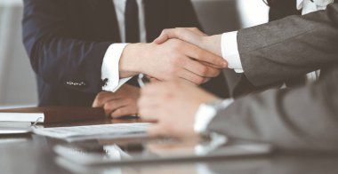 Bilinmeyen işadamı, modern ofiste iş arkadaşı ya da ortağıyla el sıkışıyor. Toplantıda iş adamları grubu