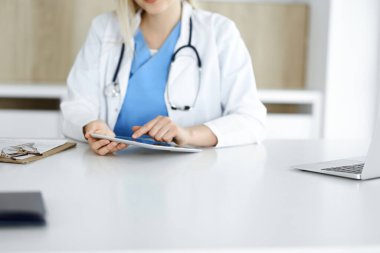 Bilinmeyen kadın doktor klinikte duruyor ve tablet bilgisayar kullanıyor, yakın plan. Veriler ve tıp ve sağlık hizmetlerindeki en iyi hizmet