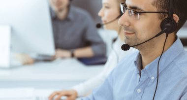 Merkezi ara. İş yerinde sıradan giyinmiş bir grup operatör. Müşteri hizmetleri ofisinde kulaklık takan yetişkin bir işadamı. İş dünyasındaki haberleşmeler