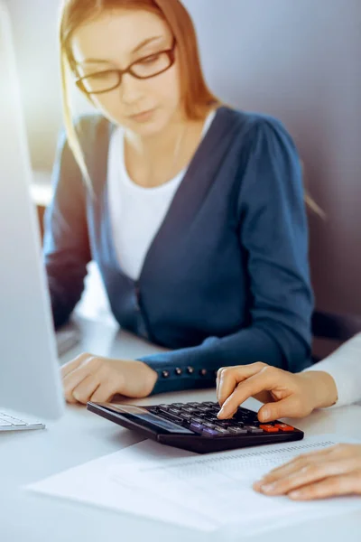 Accountant checking financial statement or counting by calculator income for tax form, hands close-up. Business woman sitting and working with colleague at the desk in office. Audit concept — Stock Photo, Image