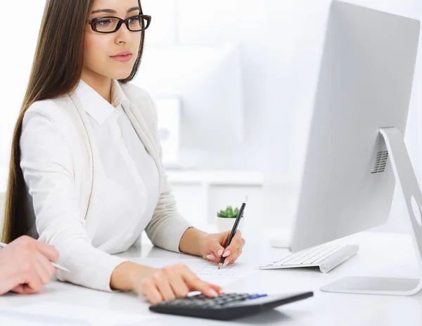 Young business woman and man sitting and working with computer and calculator in office. Bookkeeper checking balance or making finance report. Tax and audit concepts — Stock Photo, Image