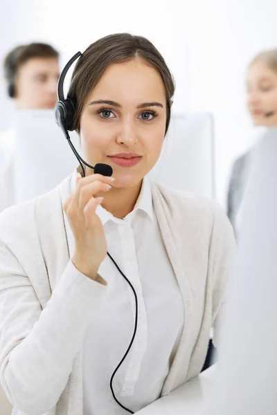 Centro de llamadas. Grupo de operadores diversos en el trabajo. Hermosa mujer en auriculares comunicándose con los clientes del servicio de telemarketing. Concepto empresarial —  Fotos de Stock