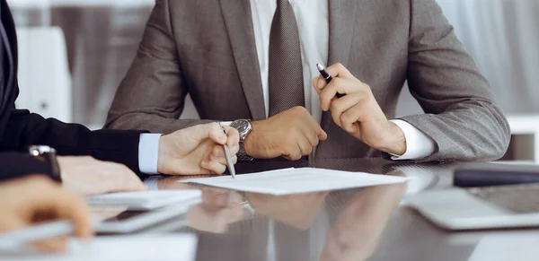 Bilinmeyen iş adamları modern ofiste birlikte çalışıyorlar, yakın plan. İş adamı ve kadın iş arkadaşları veya avukatlarıyla pazarlıkta sözleşmeyi tartışıyor